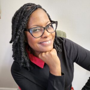 A black woman with glasses smiling